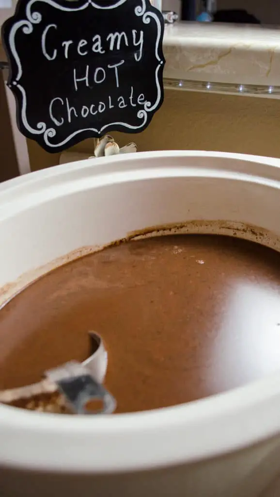 A closeup  of  a slow cooker filled with rich brown hot chocolate.