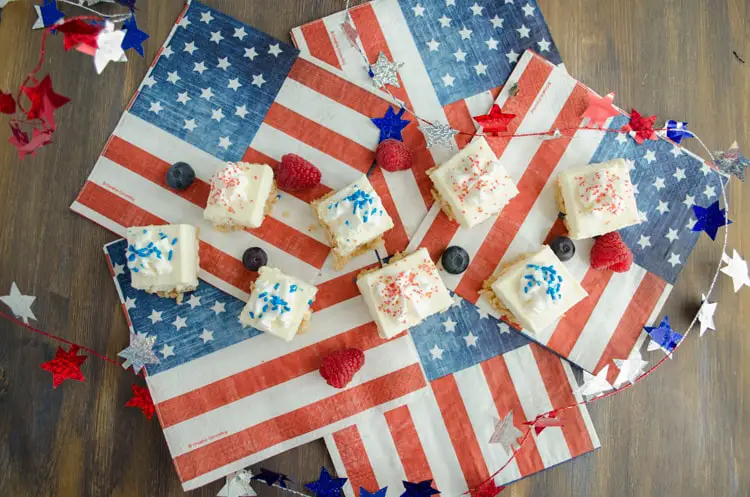 Creamy Crackle Cheesecake bars surrounded by american flags, fresh berries and a garland of stars.