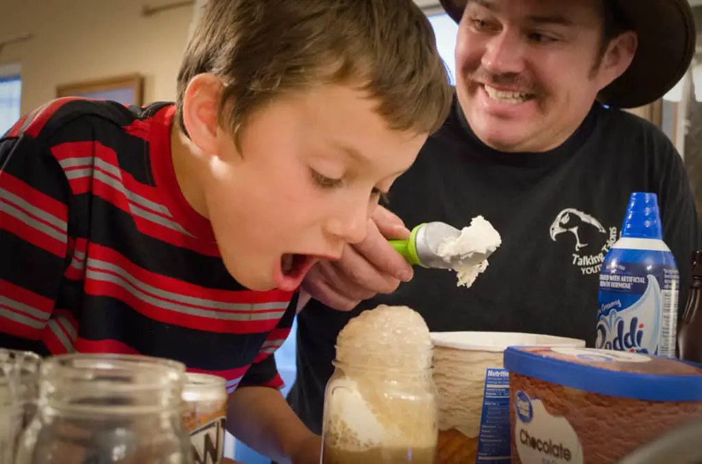 A boy watches his root beer float overflow the rim of his cup -Family Night Root Beer Float Bar