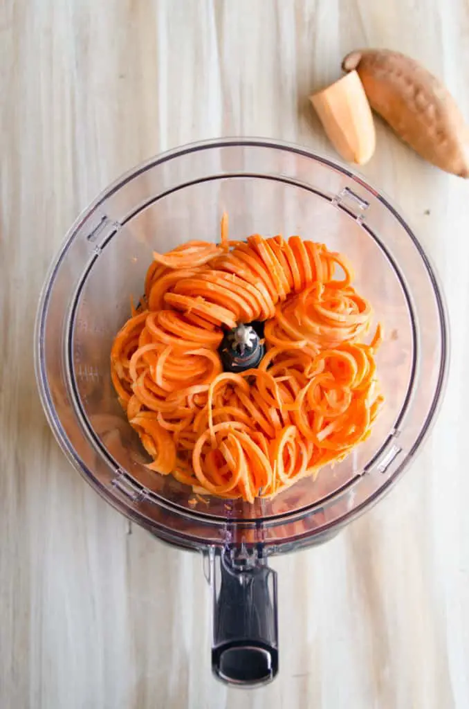 A top down view of a food processor filled with spiralized sweet potato for Crispy Southwestern Sweet Potato Fries.