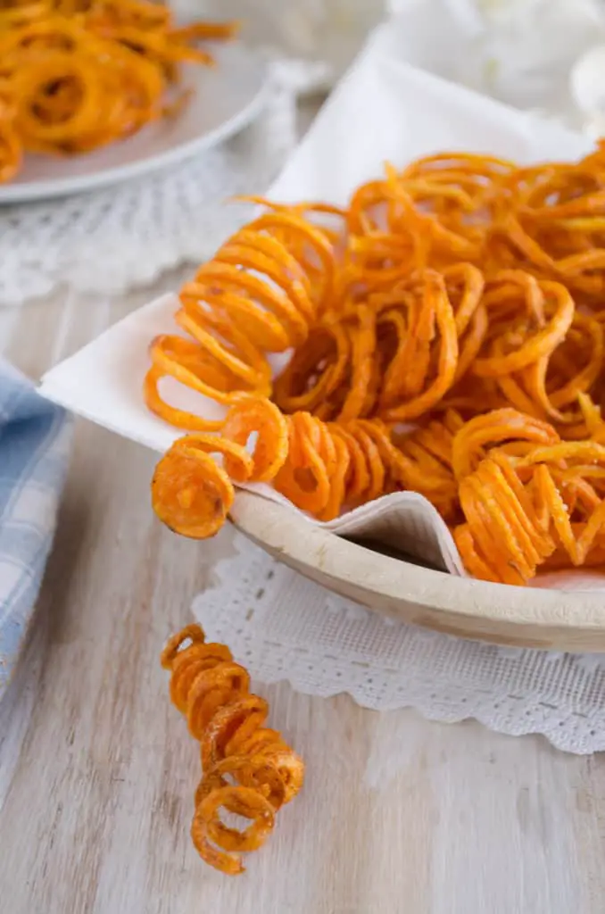 Crispy Southwestern Sweet Potato fries shaped like ringlets fill a bowl and spill over the side.