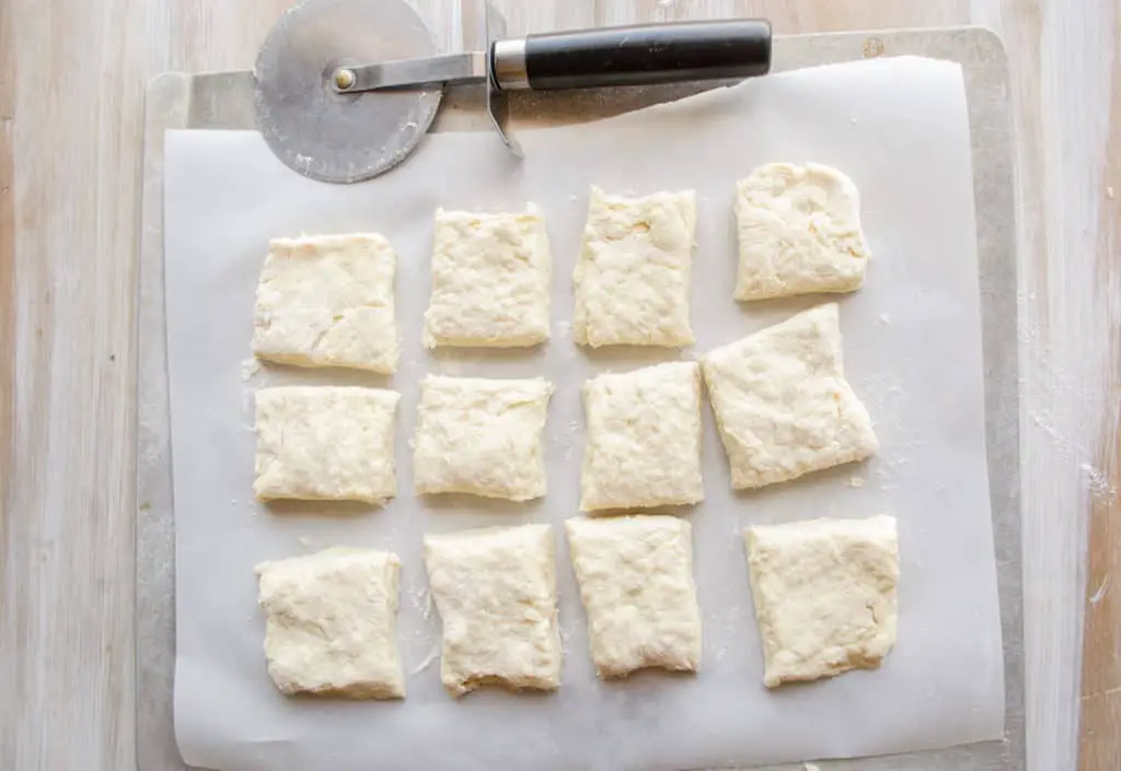 Biscuit dough for Quick Fluffy Coconut Biscuits cut into squares on a baking sheet ready for the oven.