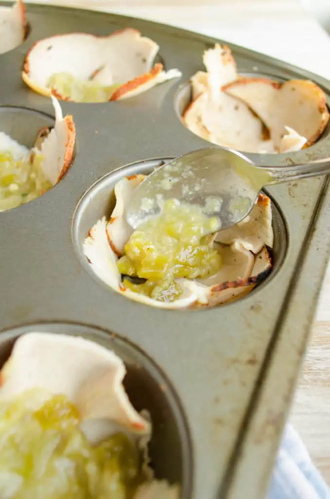 Homemade green chile sauce is spooned into a muffin tin for Green Chili Turkey Breakfast Cups.