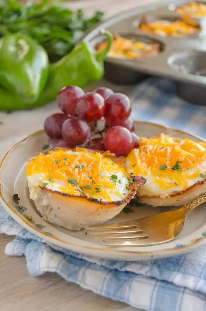 Two Green Chile Turkey Breakfast Cups sit on a plate garnished with red grapes.