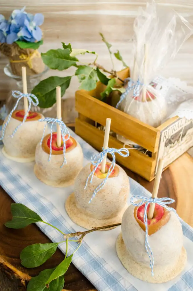 The Best Caramel Apple Recipe displayed with several apples lined in a row tied with blue bows.