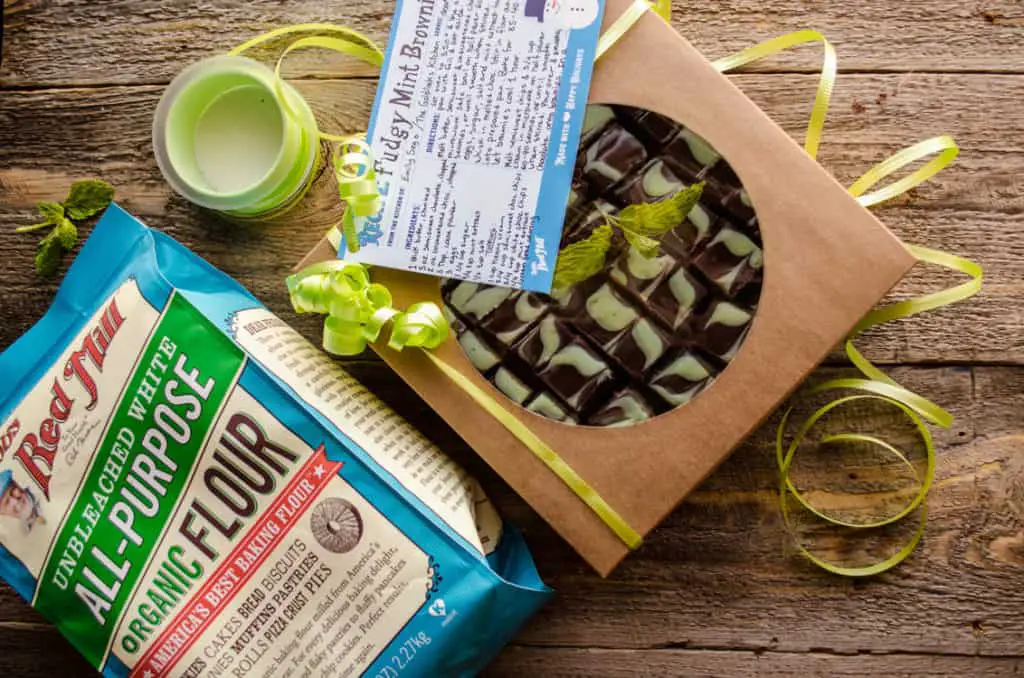Fudgy Mint Brownies packaged in a gift box tied with a green curly ribbon bow. A recipe card sits on top.