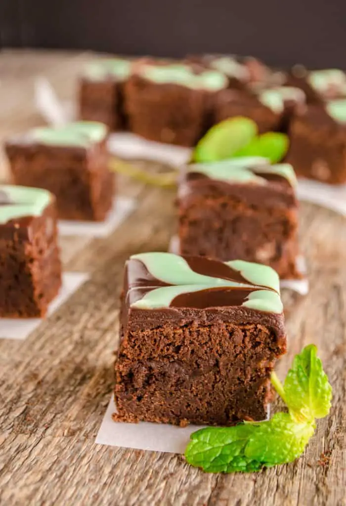 Fudgy Mint Brownies cut into individual squares on an old wooden table top.