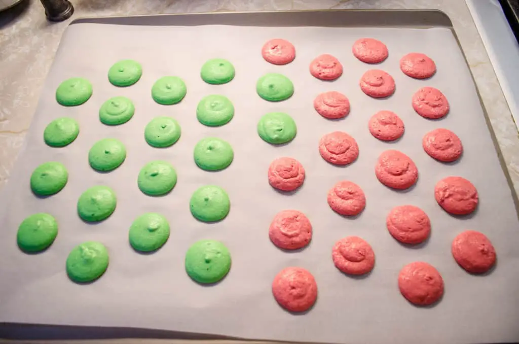 Christmas Macarons piped onto a cookie sheet waiting to be baked.