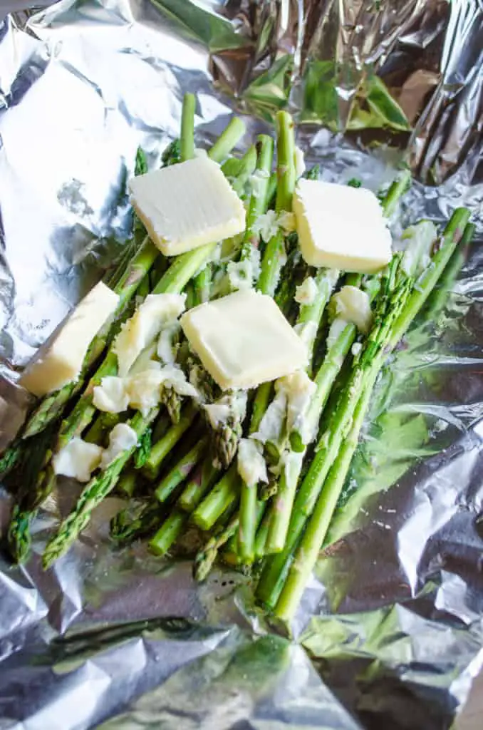 Asparagus stalks topped with pats of butter ready to be wrapped in foil for Grilled Elk Steak with Buttered Asparagus