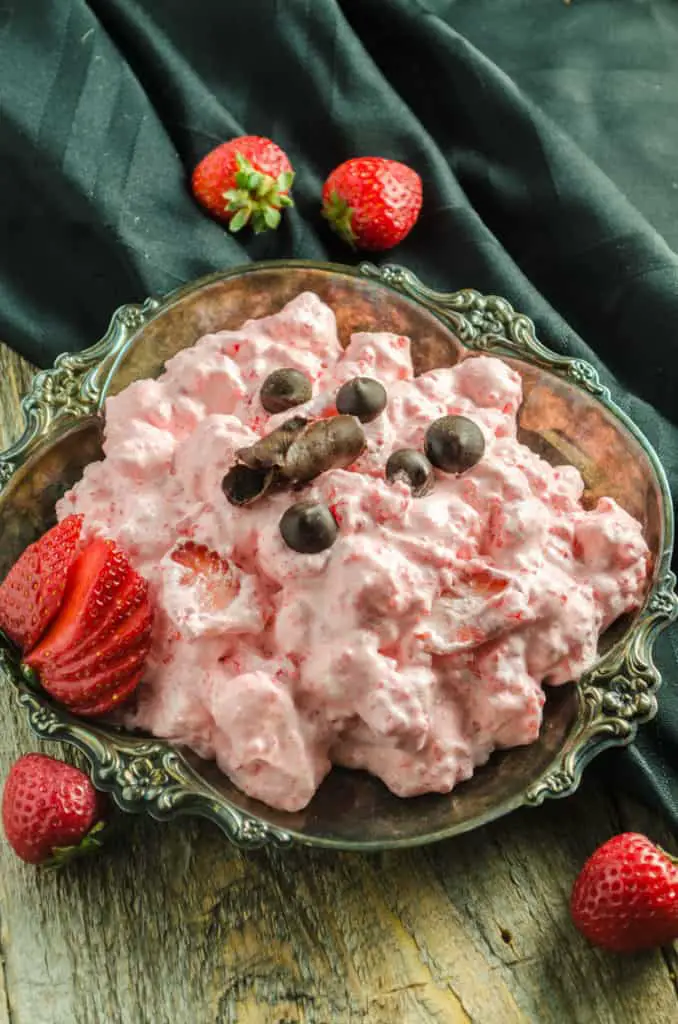 A serving of Easy Strawberry Pink Fluff garnished with fresh strawberries and chocolate.