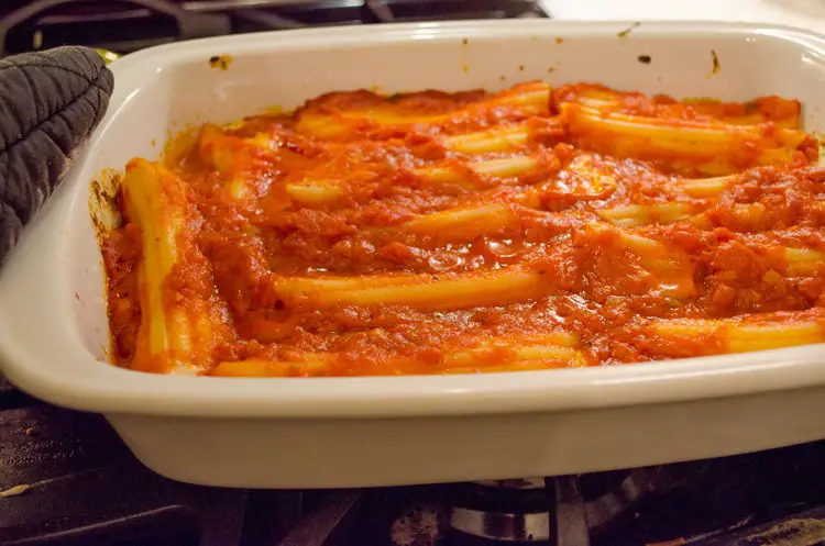 A baking dish filled with stuffed manicotti is smothered in marinara sauce for Meatless Monday Cheese Stuffed Manicotti.
