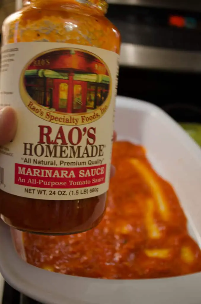 A Jar of RAO's Marinara sauce is displayed with a baking dish containing the sauce in the background.