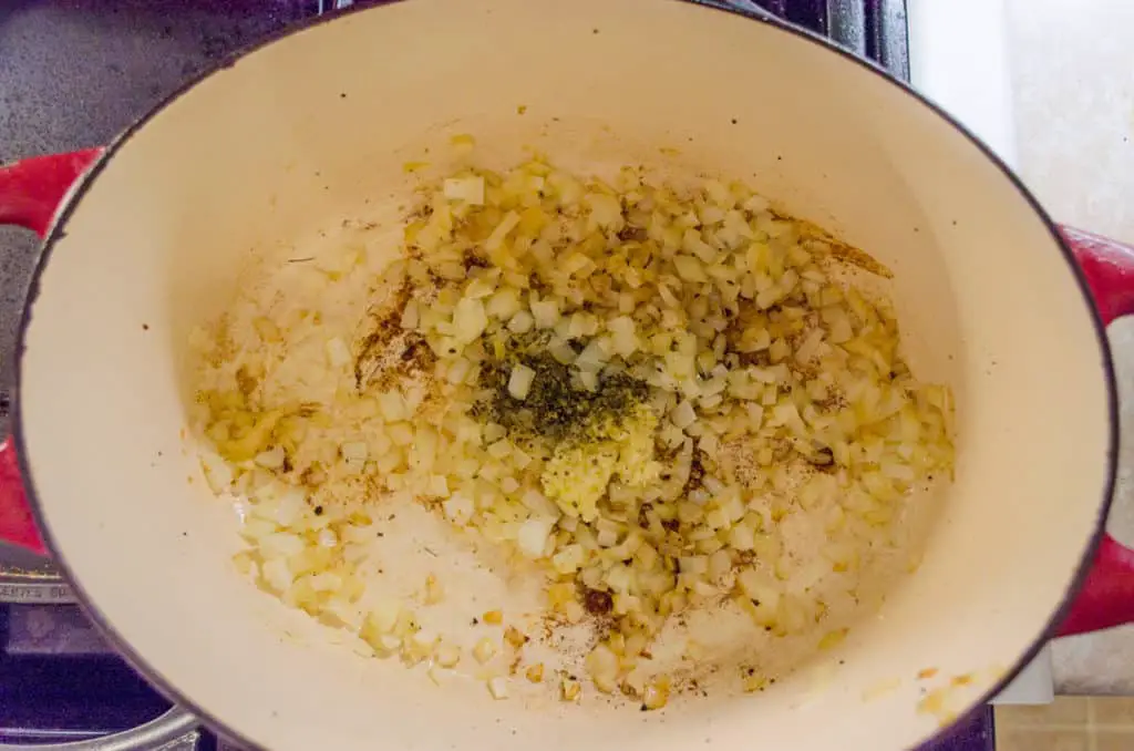 Onion, garlic, herbs and spices saute in a stovetop dutch oven for Creamy White Chicken Chili.