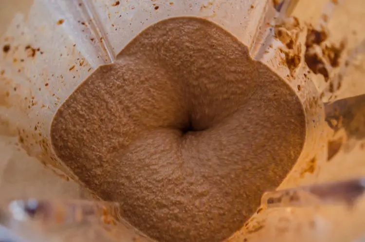 A closeup of a Peanut Butter Chocolate Banana Smoothie being blended in a blender.