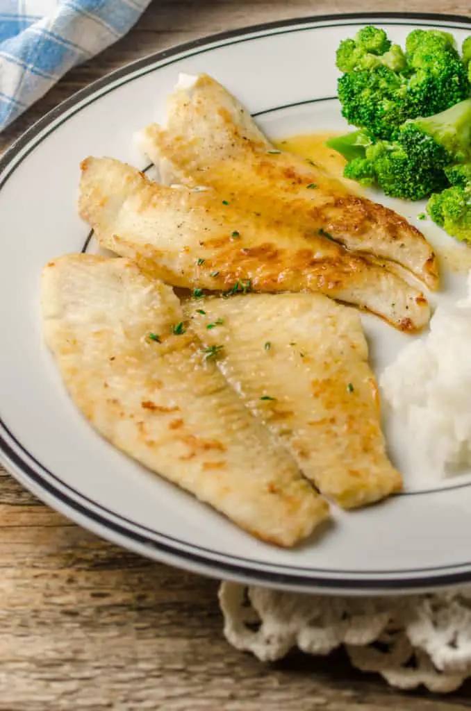 A plate of Fast Fish Dinner with Herbed Browned Butter sits with sides of rice and steamed broccoli.