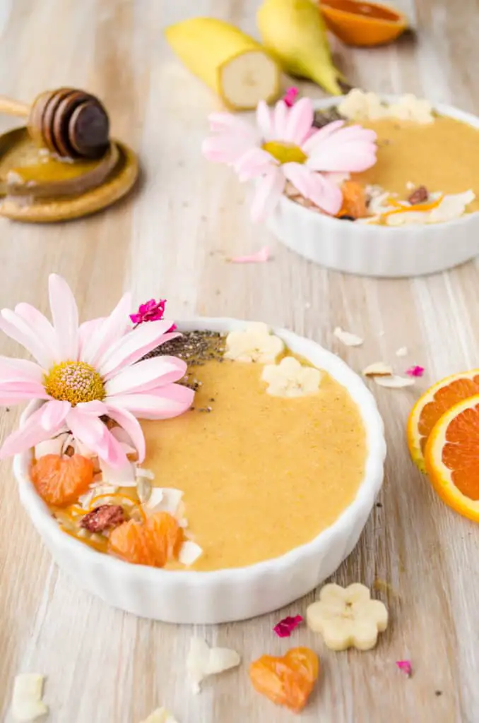 Cold Buster Smoothie Bowl surrounded by sliced oranges bananas and a honey server - The Goldilocks Kitchen