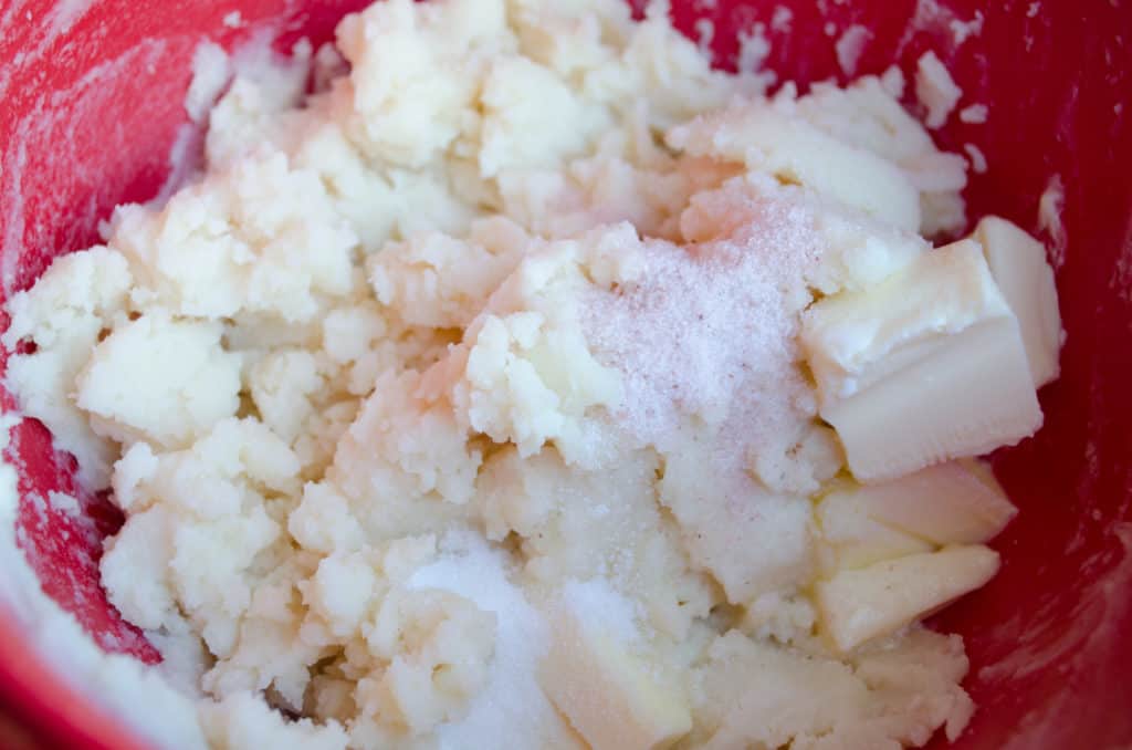 Mashed potatoes in a bowl with salt, sugar pats of butter, and cream to make Norwegian Lefse - The Goldilocks Kitchen