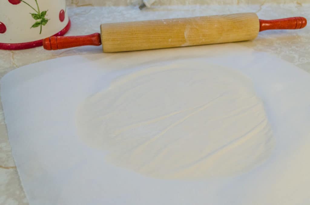 Raw Norwegian Lefse rolled out between two pieces of parchment paper- The Goldilocks Kitchen