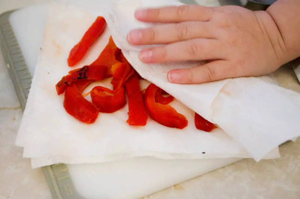 Roasted Red Bell Peppers from a jar are blotted with paper towels to remove excess oil. Will be used in Pesto Pasta with Roasted Root Veggies - The Goldilocks Kitchen
