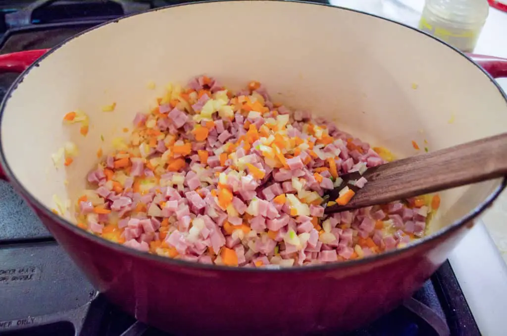 Onion, carrot and ham are cooking in a dutch oven for Creamy Split Pea and Ham Soup. - The Goldilocks Kitchen