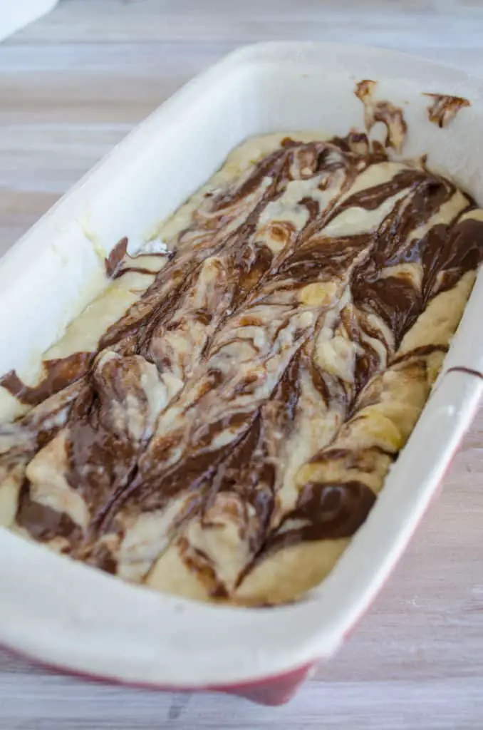 A loaf pan of banana bread batter swirled with Nutella ready to be baked - The Goldilocks Kitchen