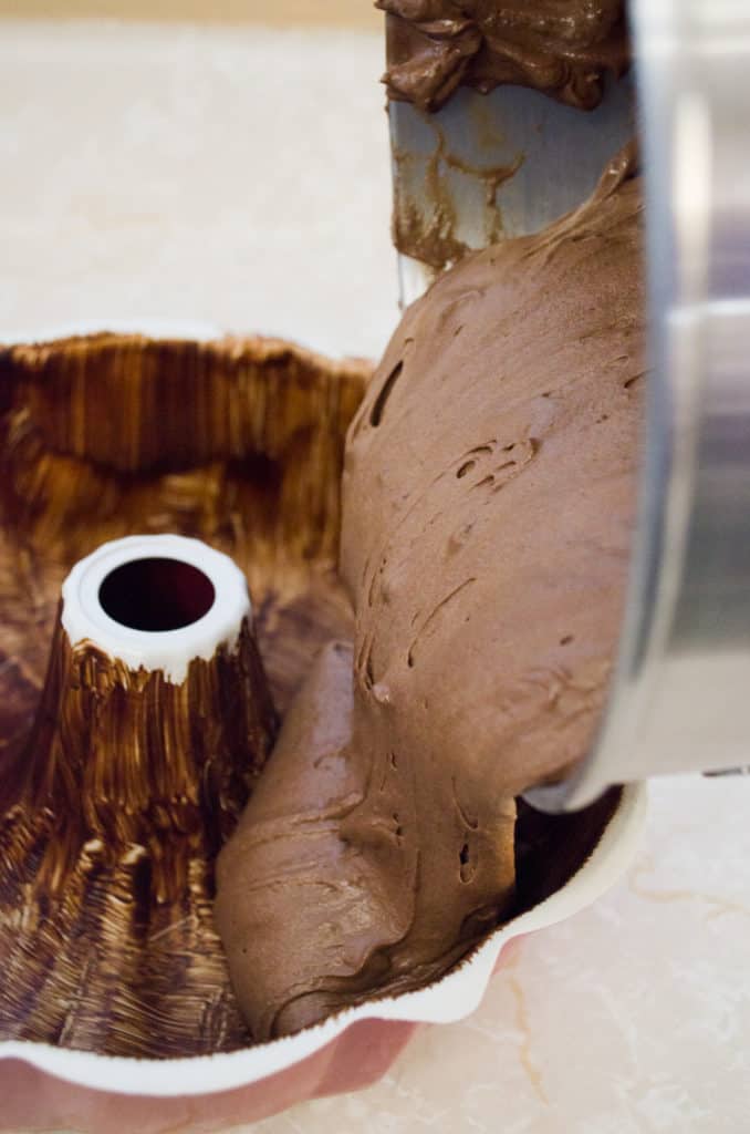 Pouring Chocolate Raspberry Bundt Cake batter into a prepared bundt pan. - The Goldilocks Kitchen