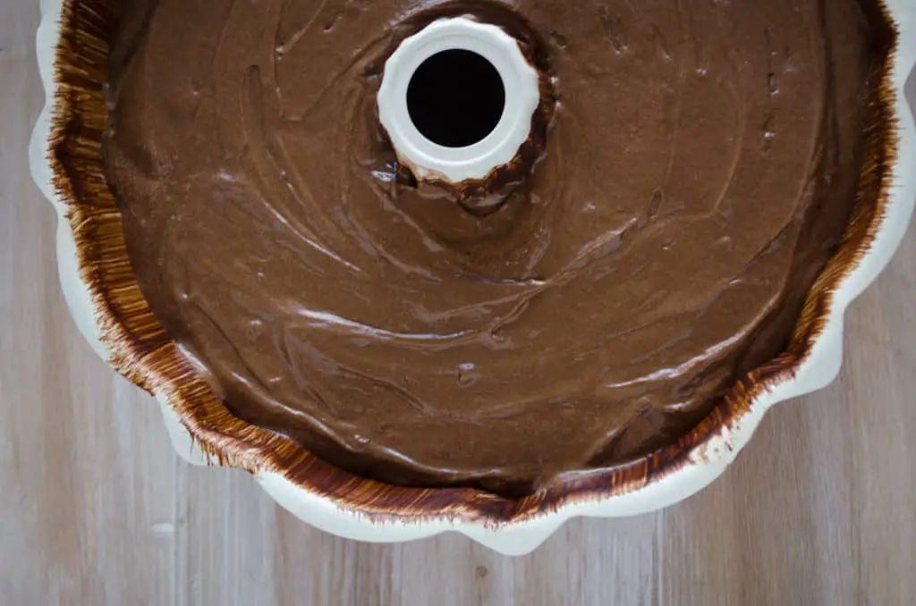 A bundt pan sits full of Chocolate Raspberry Bundt Cake batter waiting to be baked. - The Goldilocks Kitchen