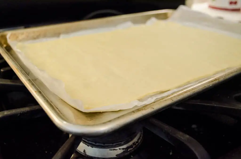 Premade pizza dough is rolled out onto a baking sheet for Nutella Pizza - The Goldilocks Kitchen