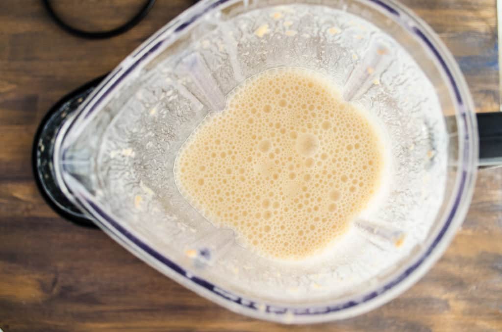 Orange Creamsicle Smoothie Pops mix sits frothy in a blender ready to be poured into molds - The Goldilocks Kitchen