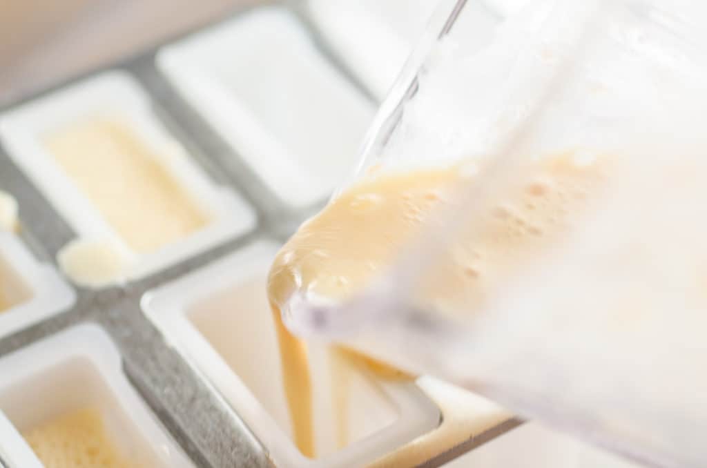 Orange Creamsicle Smoothie Pops liquid blend is poured into popsicle molds - The Goldilocks Kitchen