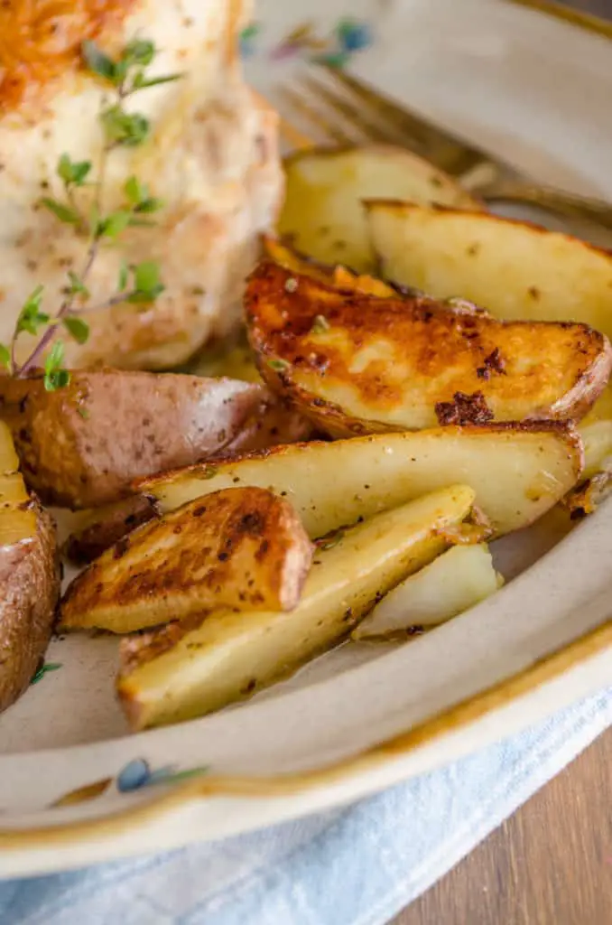 A close up of golden browned red potato wedges on a dinner plate for Weeknight Roasted Chicken Breast with Red Potatoes - The Goldilocks Kitchen