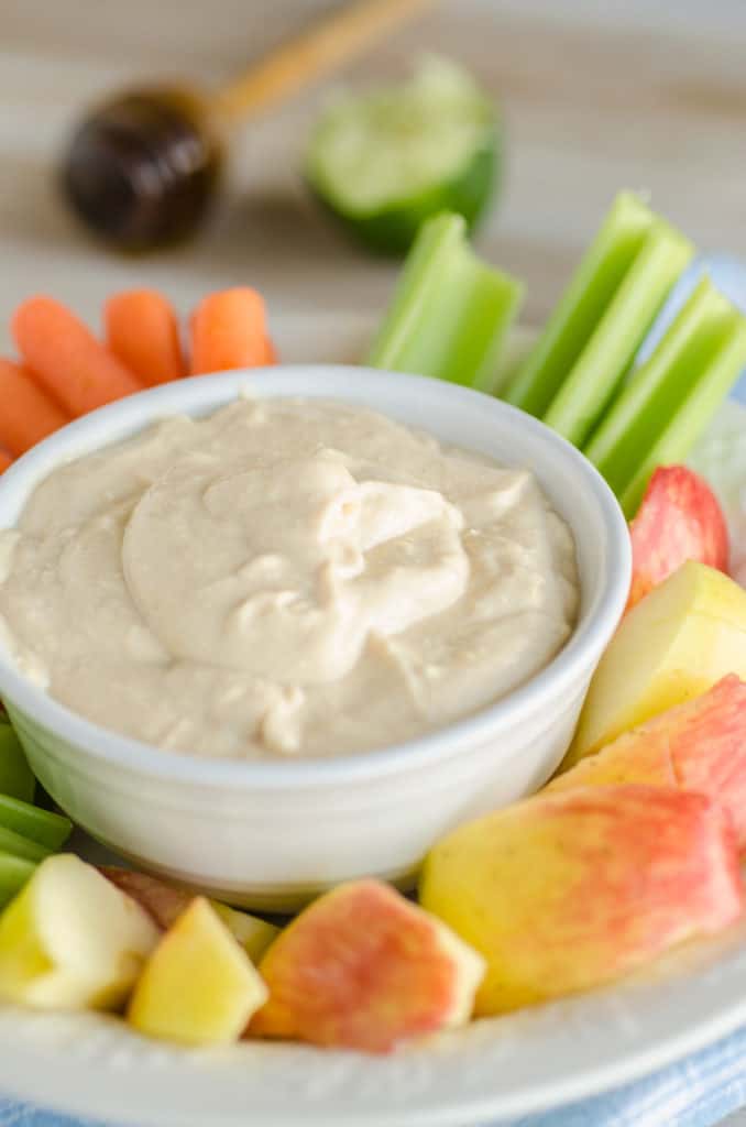 A closeup of a bowl of Silky Peanut Butter Dip with sliced apple, celery and carrots - The Goldilocks Kitchen