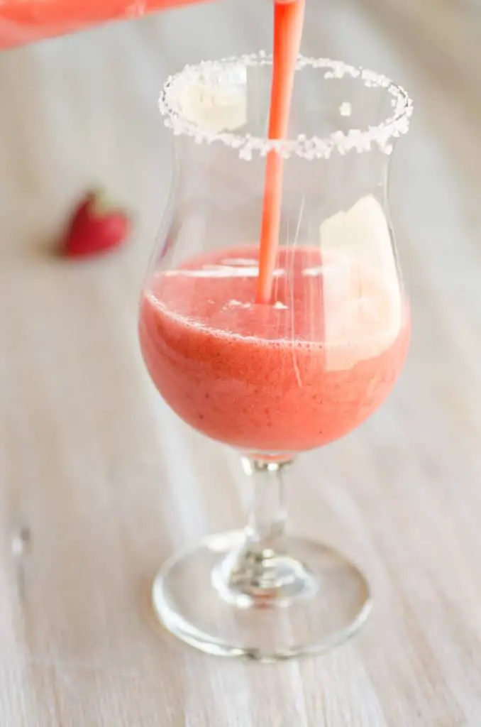 Fresh Virgin Strawberry Margaritas mixture being poured into a salted rim glass.