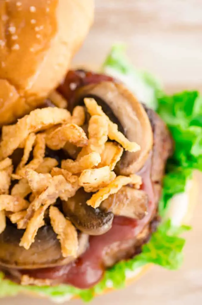 A Meatloaf Burger sits in a buttered and toasted hamburger bun topped with sauteed mushrooms and french-fried onions.