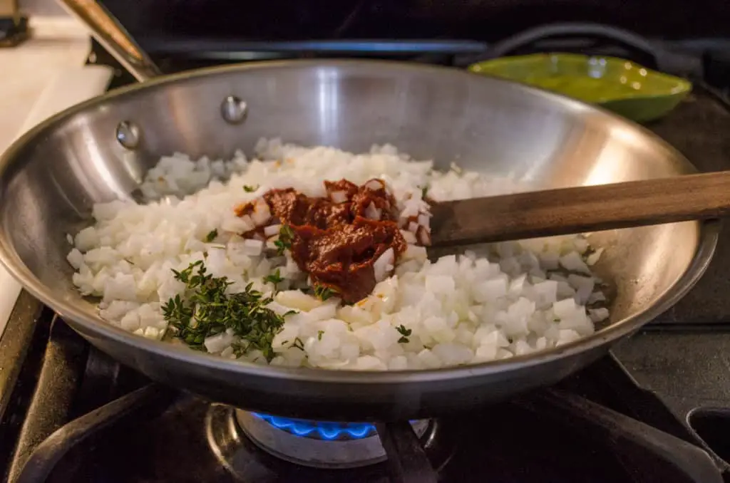 Onion, tomato paste and fresh thyme cook in a skillet for Slow Cooker Beef and Barley Stew