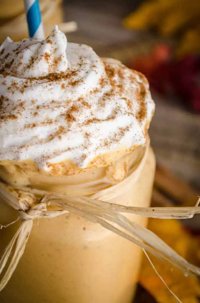 A close up of a Frosty Pumpkin Pie Smoothie with whipped cream and spices on top