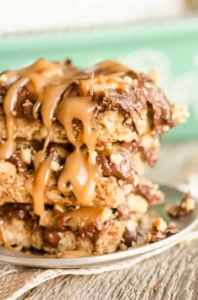 A pic of three Caramel Chocolate Oatmeal Chewies stacked and dripping with gooey caramel. -The Goldilocks Kitchen