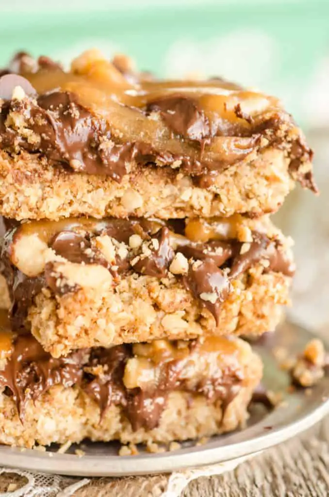 A close up pic of three Caramel Chocolate Oatmeal Chewies cookie bars stacked on top of one another. -The Goldilocks Kitchen