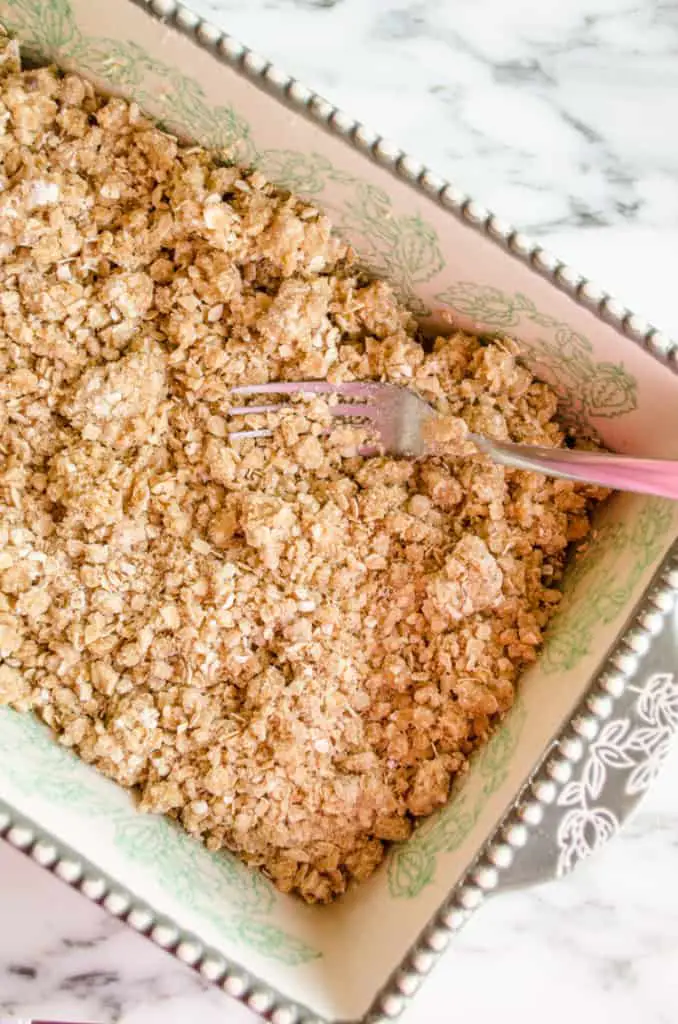 A decorative baking dish is filled with oatmeal brown sugar mixture to form the base for Caramel Chocolate Oatmeal Chewies. -The Goldilocks Kitchen