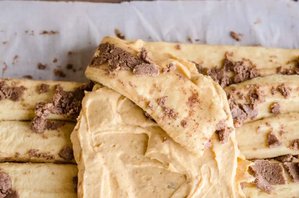 A strip of cinnamon roll dough is folded over pumpkin cream cheese filling for a Pumpkin Pie Breakfast braid - The Goldilocks Kitchen