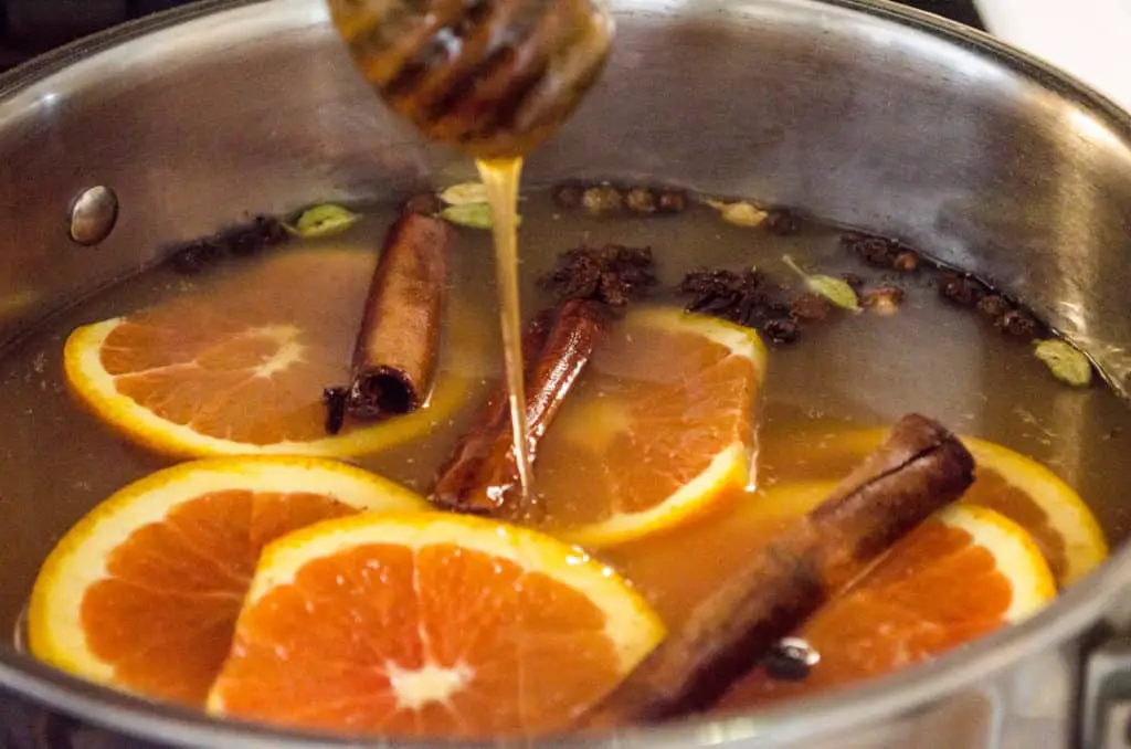 A touch of honey is added to a pot of simmering Mulled Apple Cider a.k.a. Wassail.