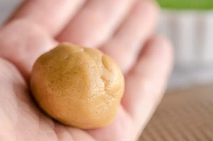 A dough ball sits in the palm of a hand for Dove Peanut Butter Buttons cookies - The Goldilocks Kitchen