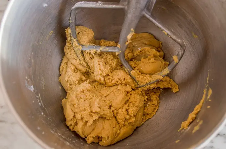 Fully mixed dough for Dove Peanut Butter Buttons cookies sits in the bowl of a stand mixer - The Goldilocks Kitchen