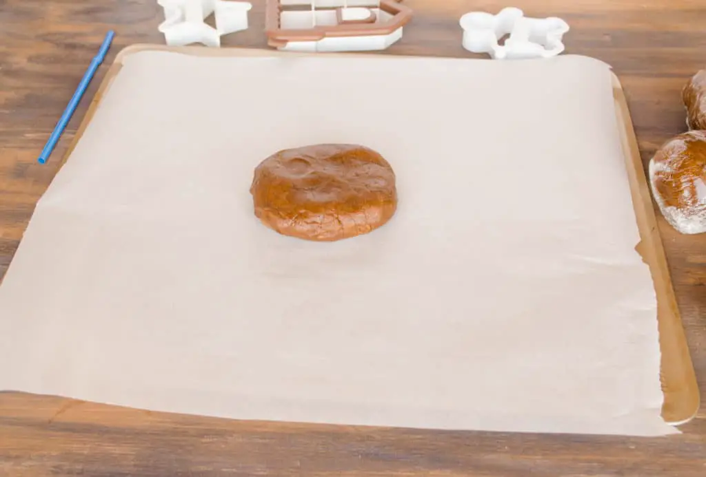  A disc of Easy Gingerbread Cookies dough sits on parchment paper surrounded with cookie cutters - The Goldilocks Kitchen
