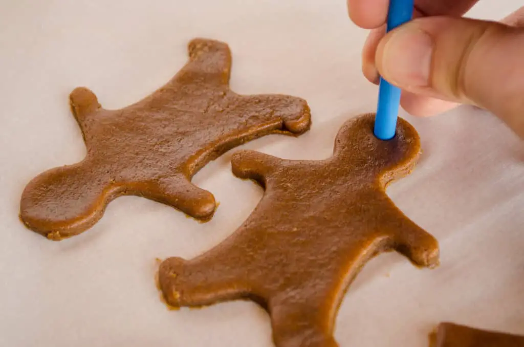  A straw is used to cut a hole in Easy Gingerbread Cookies cut out shapes so they can be hung as ornaments - The Goldilocks Kitchen