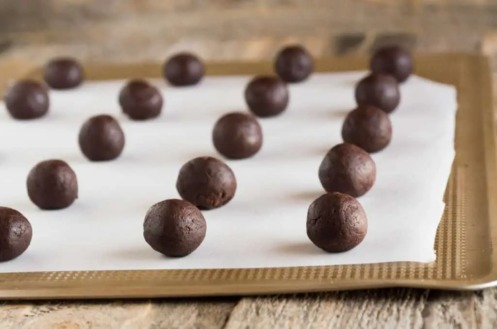Chocolate dough balls sit in rows on a baking sheet lined with parchment paper for making Homemade Oreo Cookies - The Goldilocks Kitchen
