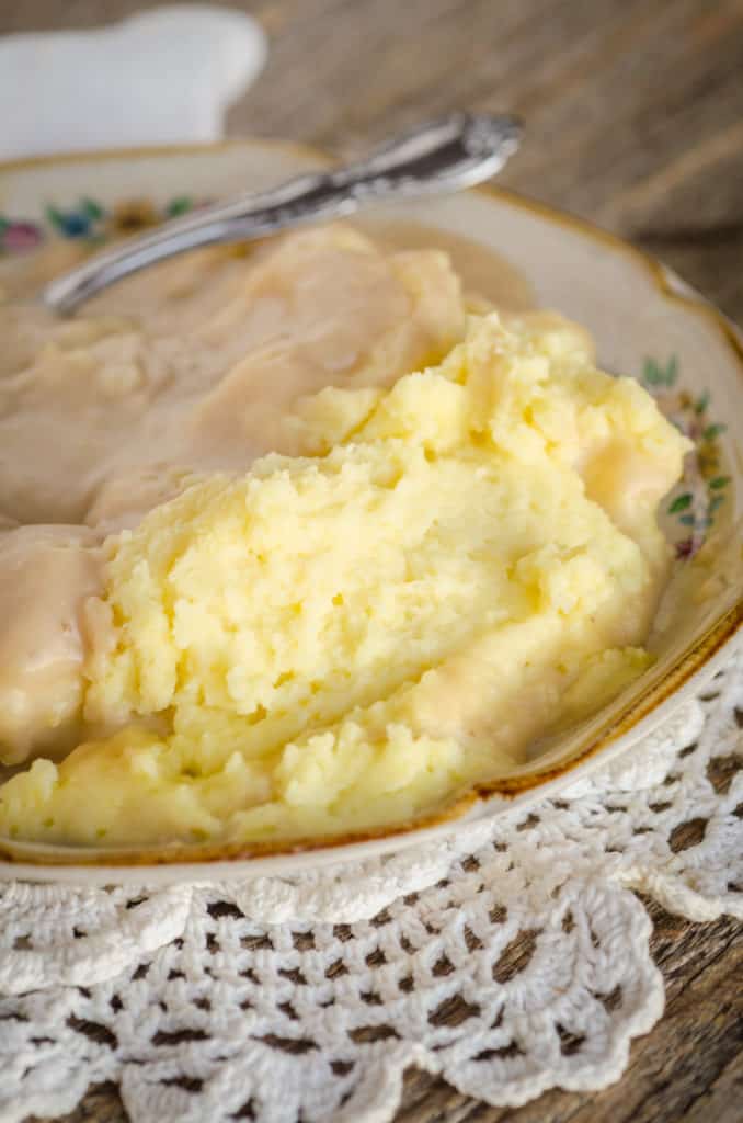 The Best Mashed Potatoes sit on a plate smothered in turkey gravy for "How to make turkey gravy" - The Goldilocks Kitchen