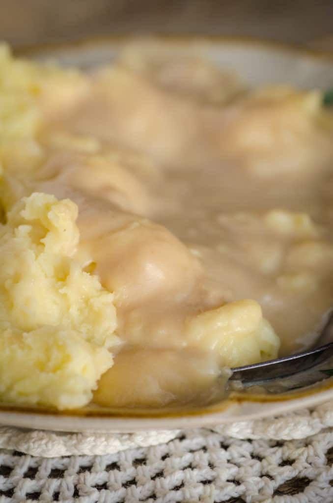 Potatoes smothered in turkey gravy on a plate for How to make Turkey Gravy - The Goldilocks Kitchen