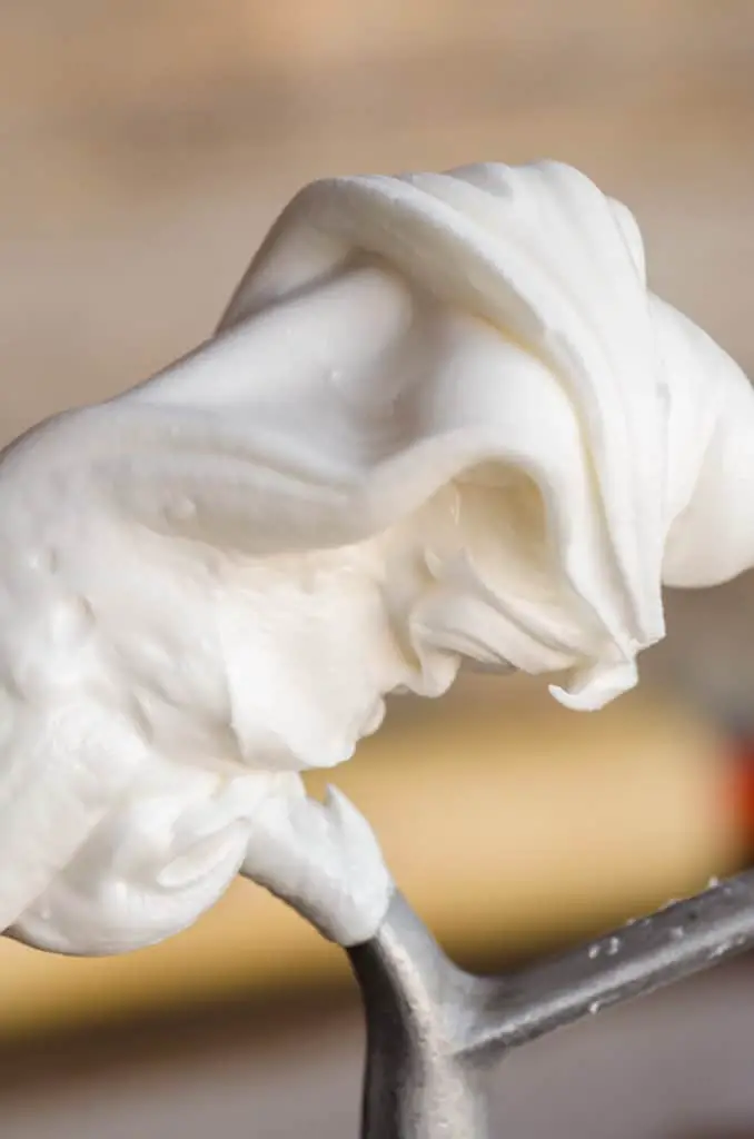 A close up picture of flowing white Royal Icing Gingerbread Frosting on the end of a stand mixer beater - The Goldilocks Kitchen