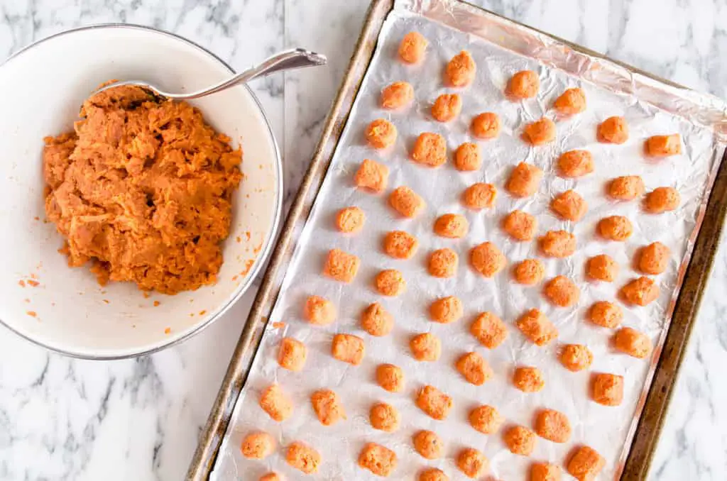 A Baking sheet lined with foil is filled with little Sweet Potato Tater Tots ready to be baked - The Goldilocks Kitchen